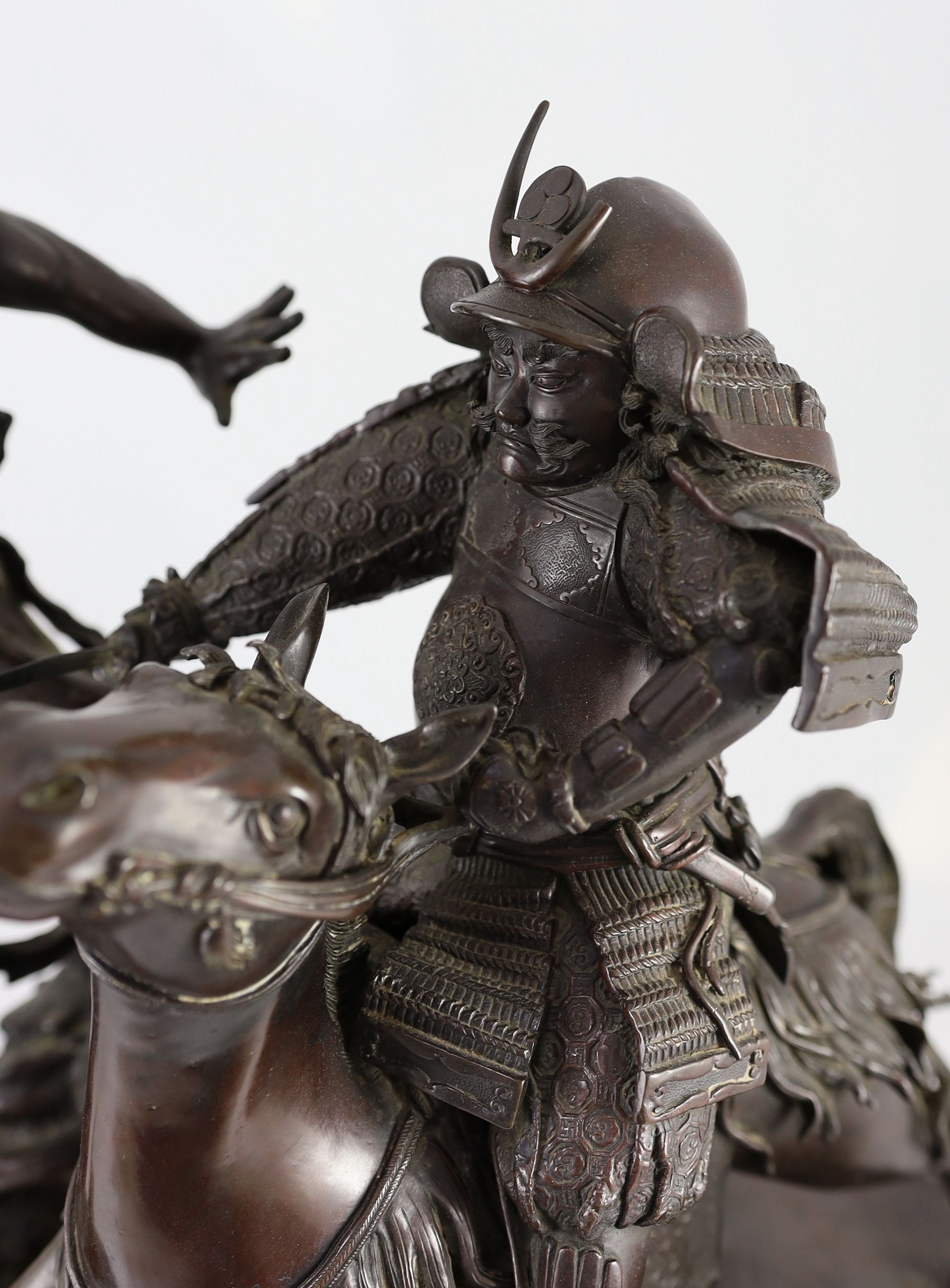 An impressive Japanese bronze group of an oni attacking a Samurai on horseback, Meiji period, 58cm high 49.5cm wide